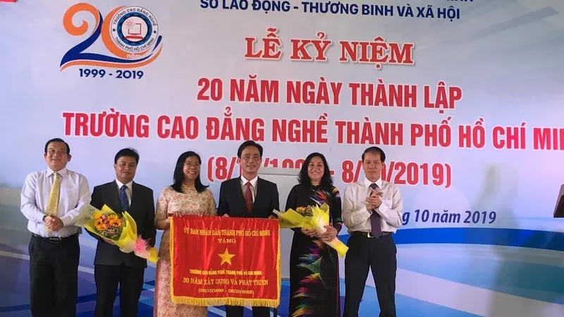 Ông Lê Minh Tấn, Giám đốc Sở LĐTB-XH TPHCM ( ngoài cùng bên trái) đại diện UBND TPHCM trao bức trướng của UBND TPHCM cho Ban Giám hiệu nhà trường