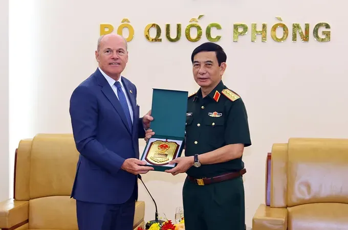 Deputy Prime Minister and Minister of National Defense General Phan Van Giang (R) offers a gift to Canadian Ambassador to Vietnam James Nickel. (Photo: BQP)