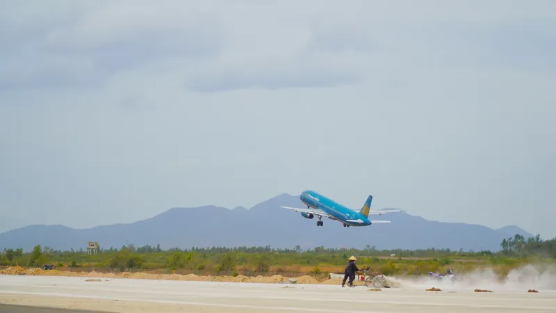 Workers use sweeping machines to clean the newly built runway at Phu Cat Airport. (Photo: SGGP)