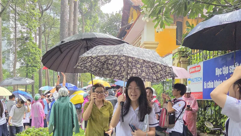 Thí sinh điểm thi THPT Trưng Vương ra về trong cơn mưa tầm tã. Ảnh: THU TÂM