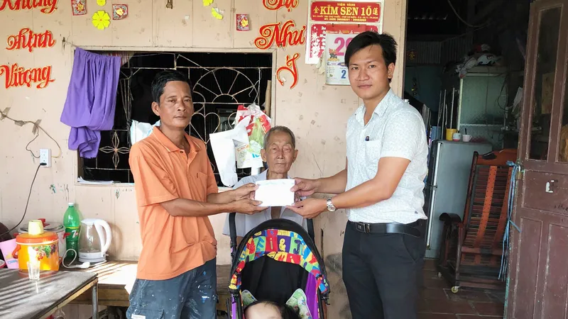 Đại diện Báo SGGP (bìa phải) trao tiền cho anh Lộc từ sự hỗ trợ của mạnh thường quân