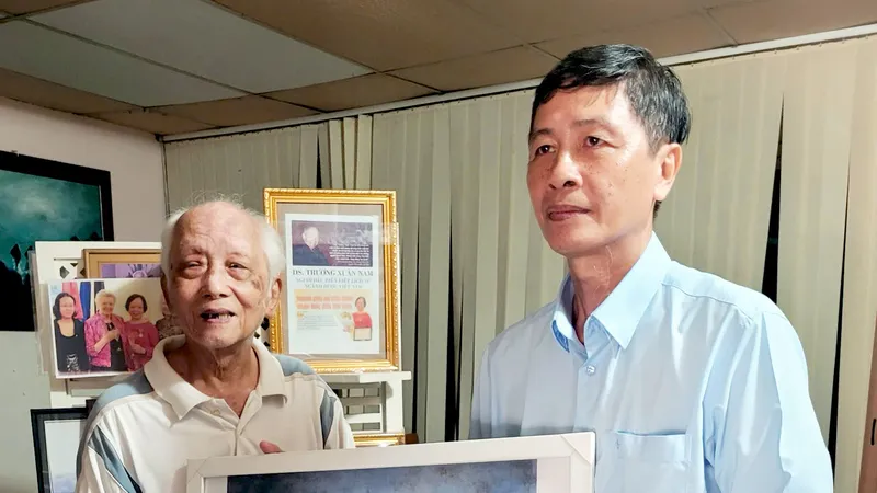 Ông Trần Tử Trung (bìa trái) tặng tranh của cha mình cho ông Lê Đình Lang