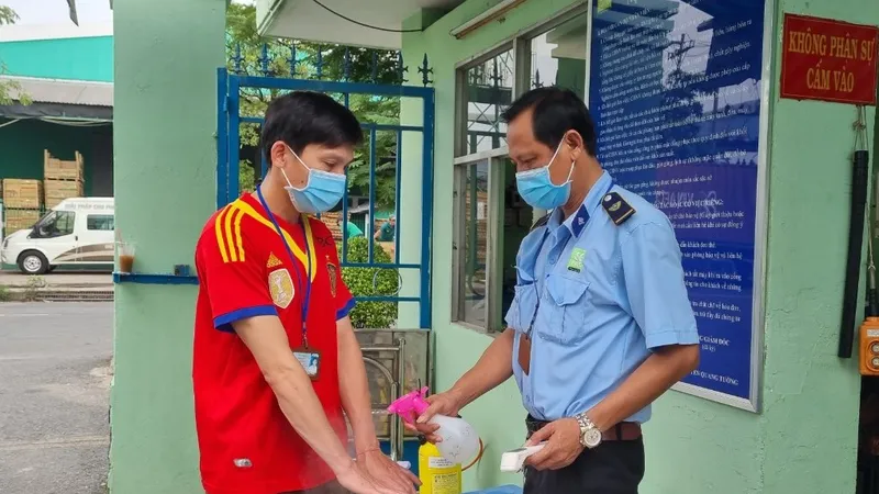 Công nhân thực hiện khử khuẩn và đo thân nhiệt trước khi vào làm việc tại doanh nghiệp trên địa bàn TPHCM