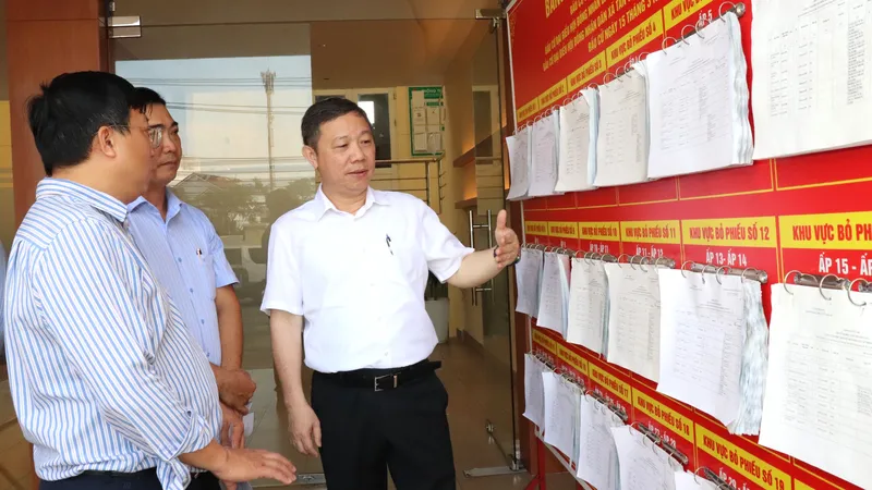 Trưởng Ban Tuyên giáo và Dân vận Thành ủy TPHCM Dương Anh Đức kiểm tra khu vực niêm yết danh sách người ứng cử tại điểm bỏ phiếu xã Tân Vĩnh Lộc. Ảnh: THÁI PHƯƠNG