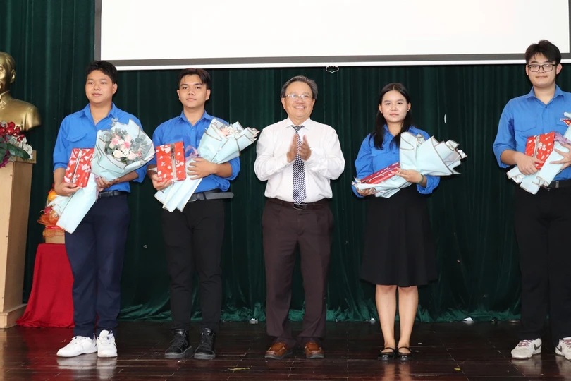 Thầy Phan Hường, Bí thư Đảng ủy, Hiệu trưởng Trường THPT Lê Thánh Tôn trao hoa và quà chúc mừng 4 đảng viên là học sinh