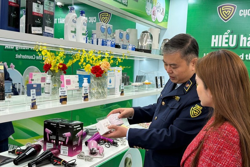 A market surveillance official guides a consumer on how to distinguish between genuine and counterfeit cosmetics. (Photo: VNA)