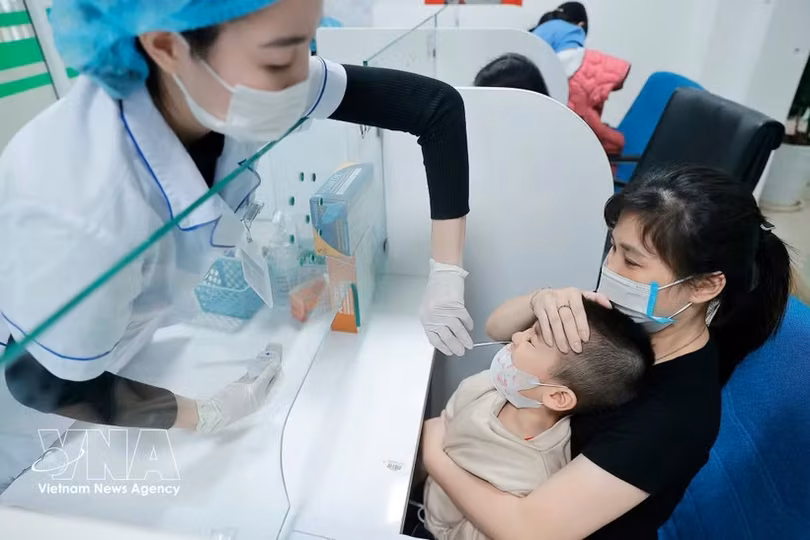 医务人员为患儿采集样本进行流感检测。图自越通社