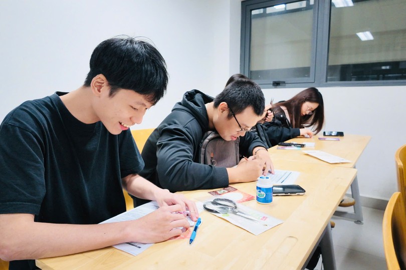 学生用造型压笔在银色锡纸上勾勒秦汉器物纹样。