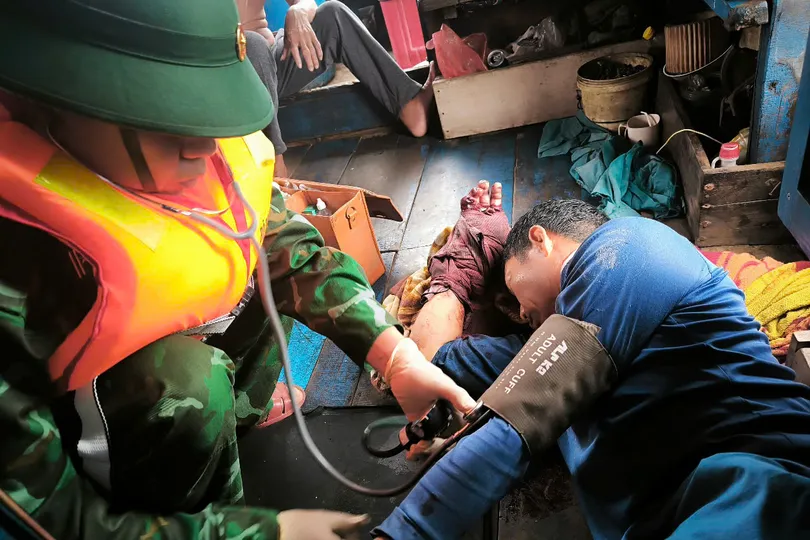Cán bộ Quân y Đồn Biên phòng Nhật Lệ đang tiến hành sơ cứu cho ngư dân bị nạn. Ảnh: ANH QUÂN