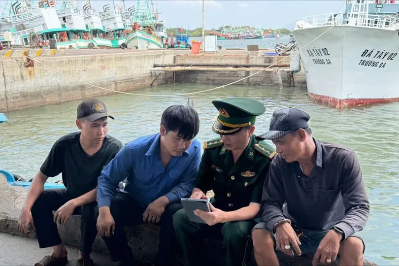 Lực lượng Biên phòng TPHCM hướng dẫn ngư dân truy cập thông tin bầu cử qua ứng dụng trên điện thoại thông minh. Ảnh: TRÚC GIANG
