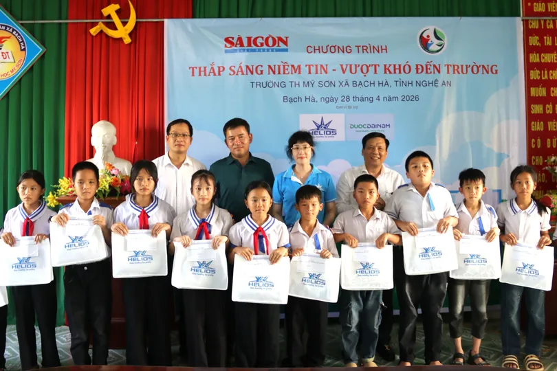 Phó Tổng Biên tập Báo SGGP Nguyễn Ngọc Anh và đại diện Công ty TNHH Dược phẩm Helios trao học bổng và quà cho các em học sinh Trường Tiểu học Mỹ Sơn