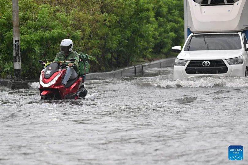 Một tài xế giao đồ ăn điều khiển xe máy băng qua vùng nước lũ ở Bangkok, Thái Lan, ngày 6-10. Ảnh: THX 