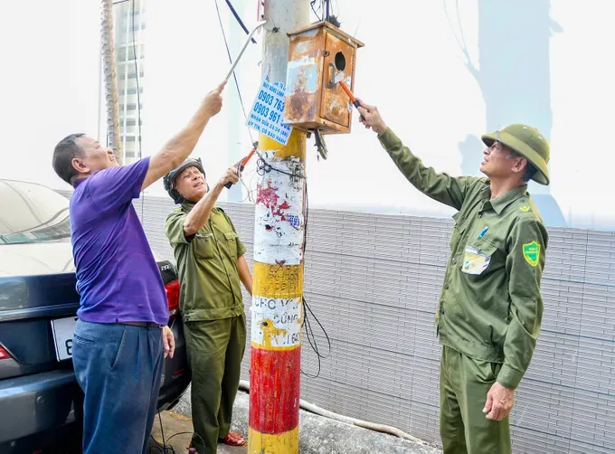 Grassroots security forces and residents of Tam Thang Ward are eradicating illegal advertisements (Photo: SGGP)