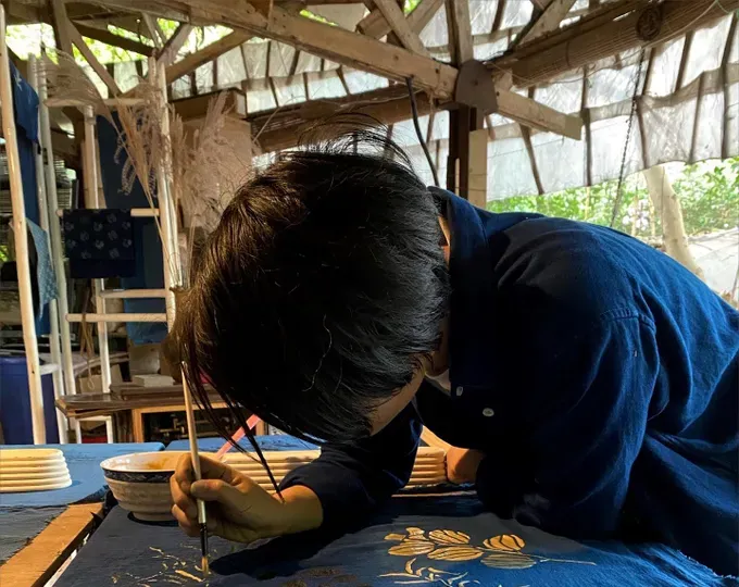 An incredibly focused artisan is painting directly onto the silk fabric strictly following the manual indigo dyeing process (Photo: Do Do Lamp shop)