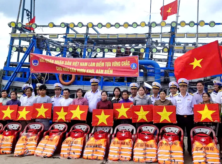 Tặng cờ Tổ quốc, áo phao, phao cứu sinh, túi y tế cho ngư dân tại cảng cá Bình Châu. Ảnh: THÀNH HUY