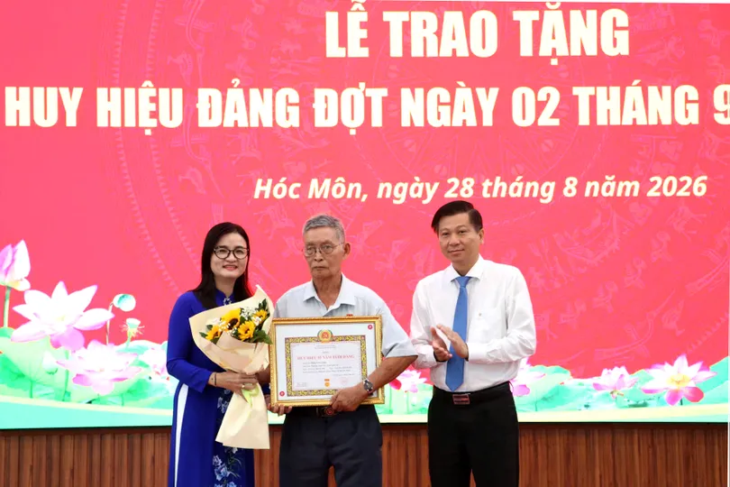 Đồng chí Trần Văn Tuấn - Ủy viên Ban Thường vụ Thành ủy, Trưởng Ban Nội chính Thành ủy TPHCM và Bí thư Đảng ủy xã Hóc Môn Lê Thị Ngọc Thanh trao Huy hiệu 55 năm tuổi Đảng đến đảng viên lão thành. Ảnh: NGÔ BÌNH