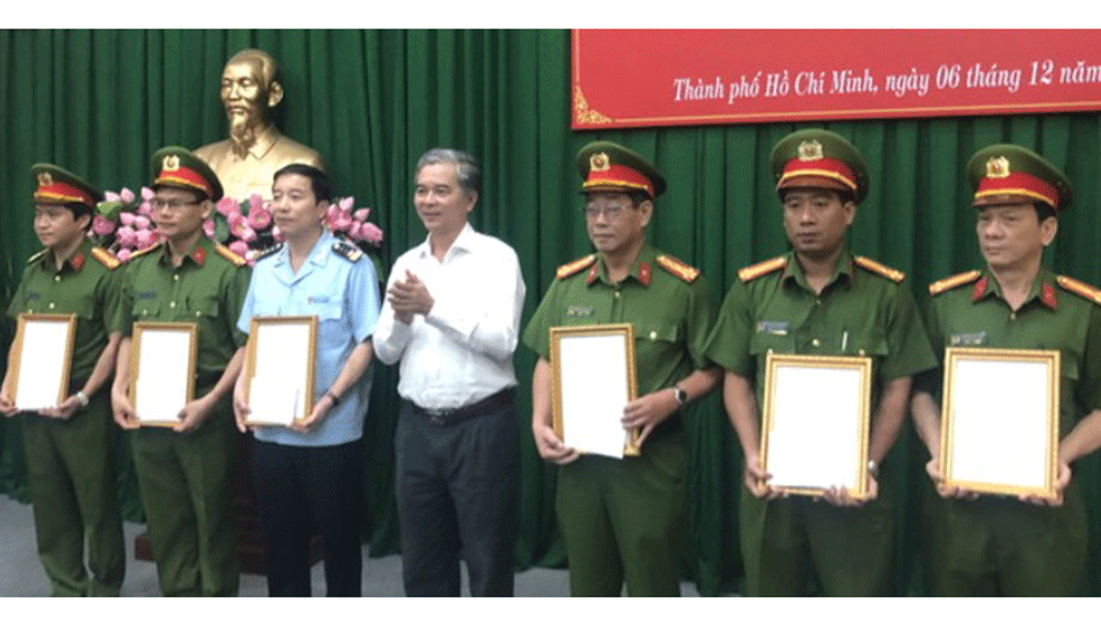 Deputy Chairman Ngo Minh Phong gives certificates of merit to police officers (Photo: SGGP)