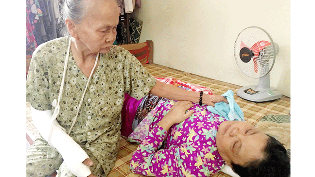 Bà Nghĩa với cánh tay bó bột, bên con gái Đặng Thị Mai Hương bị ung thư không tiền chữa trị