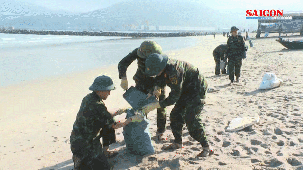 Sáng 17-2, lực lượng chức năng thu gom dầu tràn lẫn vào cát dọc bờ biển xã Kỳ Lợi 