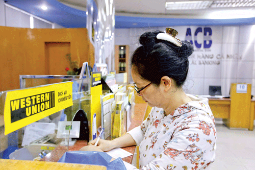 Khách hàng nhận kiều hối qua kênh Western Union. Ảnh: LONG THANH Khách hàng nhận kiều hối qua kênh Western Union. Ảnh: LONG THANH
