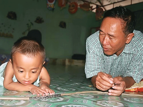 Anh Tôn Thất Hưng bên cháu bé bệnh xương thủy tinh đang được Công ty Cá sấu Hoa cà chăm sóc. Ảnh: THU HỒNG