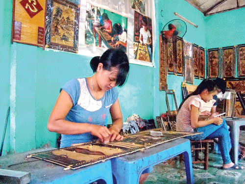 Chị Nguyễn Thị Hà đang khắc tranh trên phên tre.