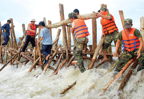 Bộ đội Trung đoàn I - Sư đoàn bộ binh 330 (QK9) cùng lực lượng dân quân địa phương suốt đêm ngâm mình ngăn lũ hàn gắn tuyến đê Kênh 7 (An Giang) Ảnh: VĂN TRANH
