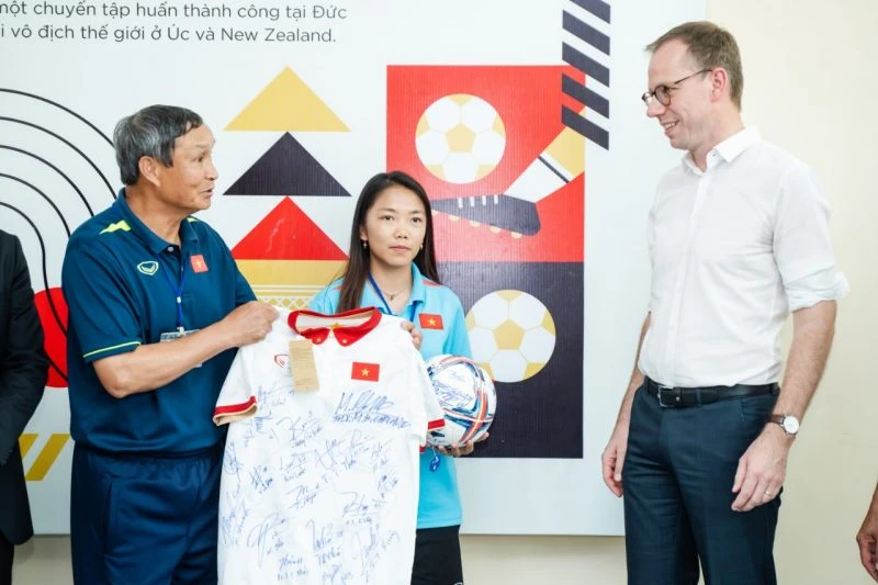 HLV Mai Đức Chung và đội trưởng Huỳnh Như trao tặng bóng và áo có chữ ký của toàn đội đến Phó Đại sứ Simon Kreye