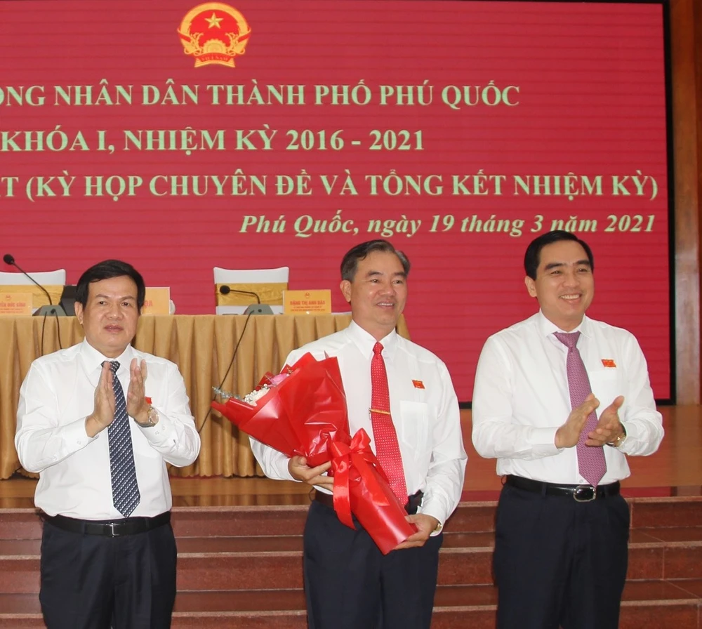 Chủ tịch HĐND TP Phú Quốc Nguyễn Đức Kỉnh (trái) và Chủ tịch UBND TP Phú Quốc Huỳnh Quang Hưng (phải) tặng hoa chúc mừng ông Đoàn Văn Tiến. ẢNH: HOÀNG DUNG