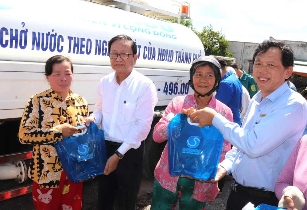  Ông Nguyễn Thanh Sử (thứ 2 bên trái), Phó Tổng giám đốc SAWACO, trao tặng túi nước sạch đến người dân xã Phú Đông, huyện Tân Phú Đông (tỉnh Tiền Giang)