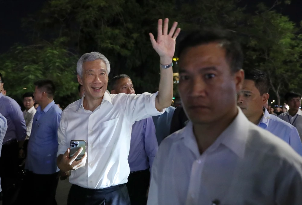 Thủ tướng Singapore Lý Hiển Long chào người dân khi dạo phố đi bộ bên hồ Hoàn Kiếm và thăm đền Ngọc Sơn, tối 27-8. Ảnh: QUANG PHÚC