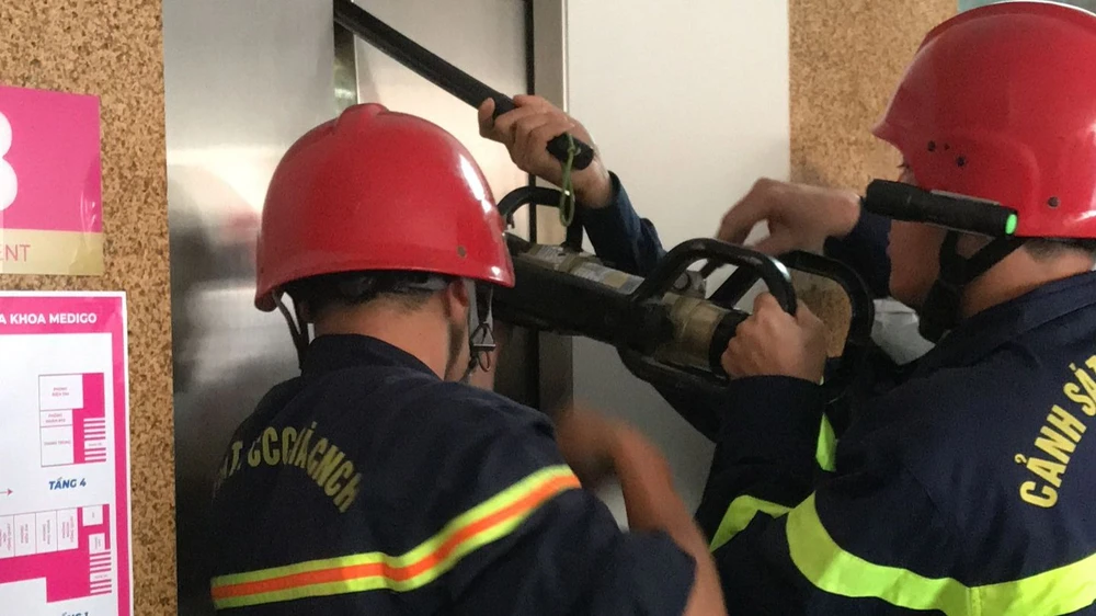 Lực lượng PCCC TPHCM dùng dụng cụ chuyên dụng phá cửa thang máy, đưa 9 nạn nhân mắc kẹt bên trong ra ngoài