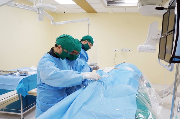 Doctors perform the operation on the elderly woman to palce stent (Photo: SGGP)