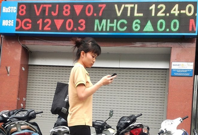 A woman walks past an electronic board showing share prices at Bao Viet Securities Co on Ba Trieu street in Hanoi (Photo: VNA)