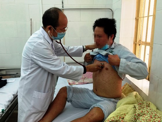 A medical worker is examining an adult suffering measles in Hanoi (Photo: SGGP)