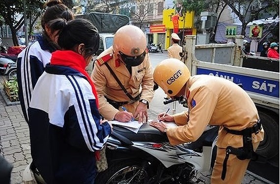 Police officers write ticket to fine two students who violate the traffic law (Photo: SGGP)