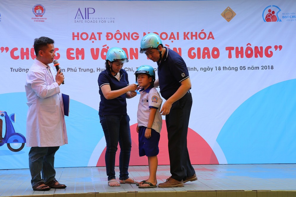 A  student is instructed how to wear helmet corectly (Photo: SGGP)