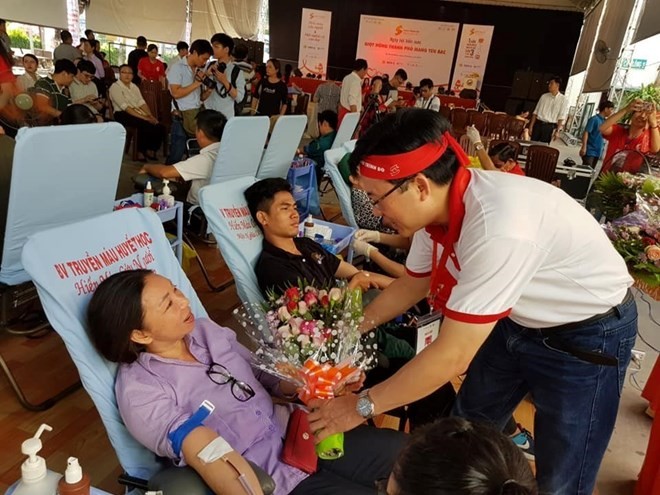 A member of the Red Journey's organising board presents flowers to a blood donor at the blood donation event in HCM City on June 22 (Photo: VNA)