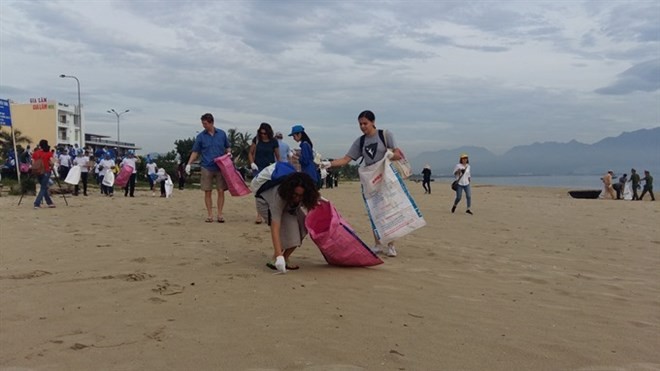 Participants at the 6th Global Environment Facility Assembly join hands to clean the beach in Da Nang city (Source: VNA)