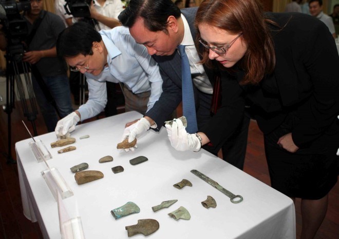 Officials examine the antiques at the hand-over ceremony (Photo: VNA)