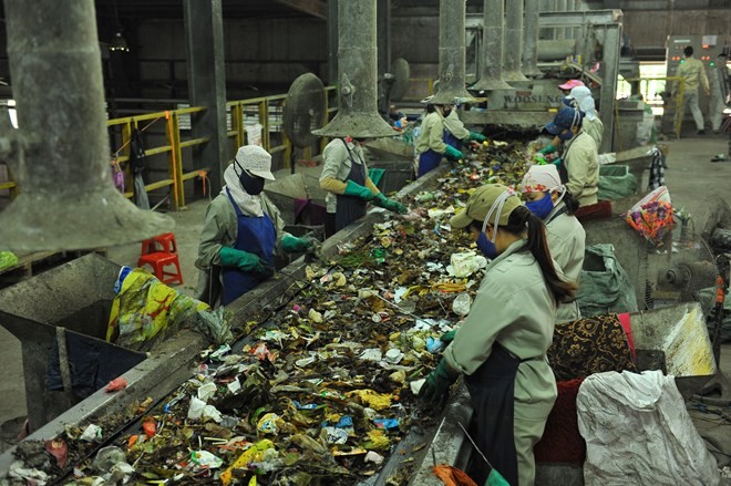 Workers sort waste at a waste treatment factory (Photo: VNA)
