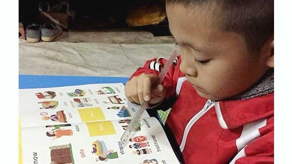 8-year-old Nguyen Thanh Dat  is reading his English book (Photo: SGGP)