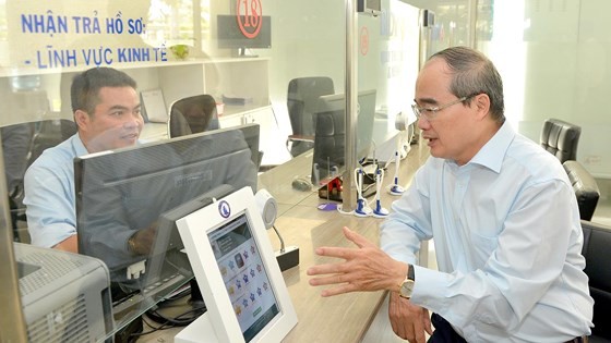 HCMC Party Leader Nguyen Thien Nhan (R) talks to a public servant in District 12 about residents’ satisfaction with administrative procedures (Photo: SGGP)