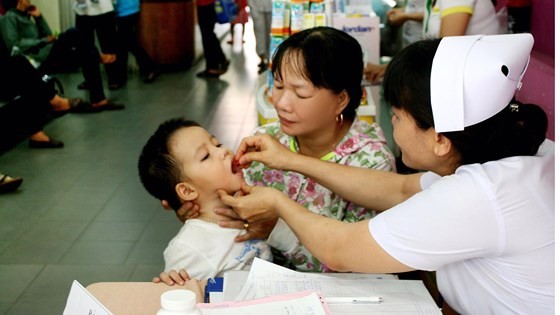 A medical worker gives Vitamin A to a kid (Photo: SGGP)