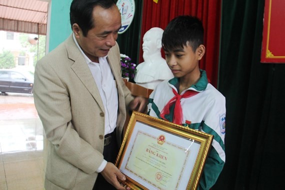 Director of the Ha Tinh Department of Education and Training Tran Trung Dung gives Certificate of Merit to seventh grader Nguyen Van Chuong (PHoto: SGGP)