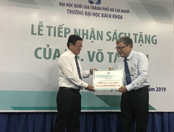 Deputy chairman of Committee for Overseas Vietnamese Vo Thanh Chat (L) gives the books to HCMCUT representative (Photo: SGGP)