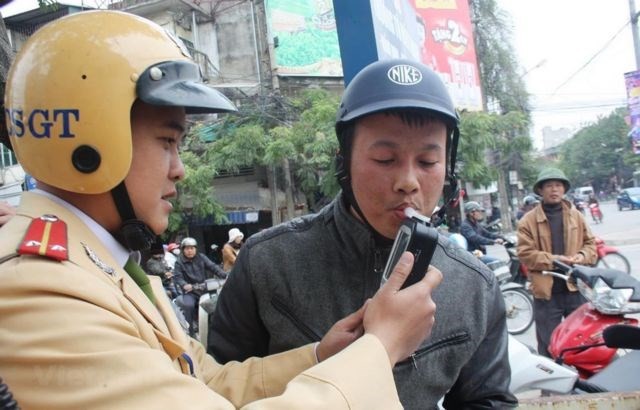 A traffic police officer takes an alcohol test for a motorcyclist. (Photo: VNA)
