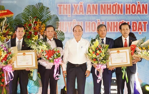 PM Phuc ( white) gives certificates to recognize the two communes to achieve the government's new rural plan (Photo: SGGP)