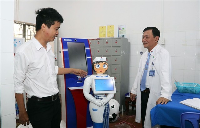 Vo Hong Quan, director of the Centre of Information and Technology under the Eastern People Military Hospital in HCM City (left), introduces the nurse robot named Tam (Photo:VNA)