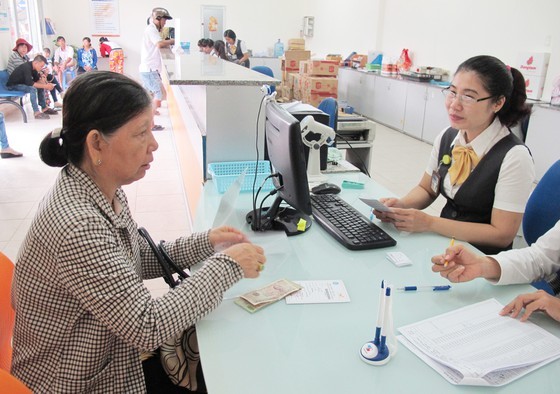 An elderly woman receives retirement salary and insurance in a post office in Binh Chanh Dsitrict (Photo: SGGP)